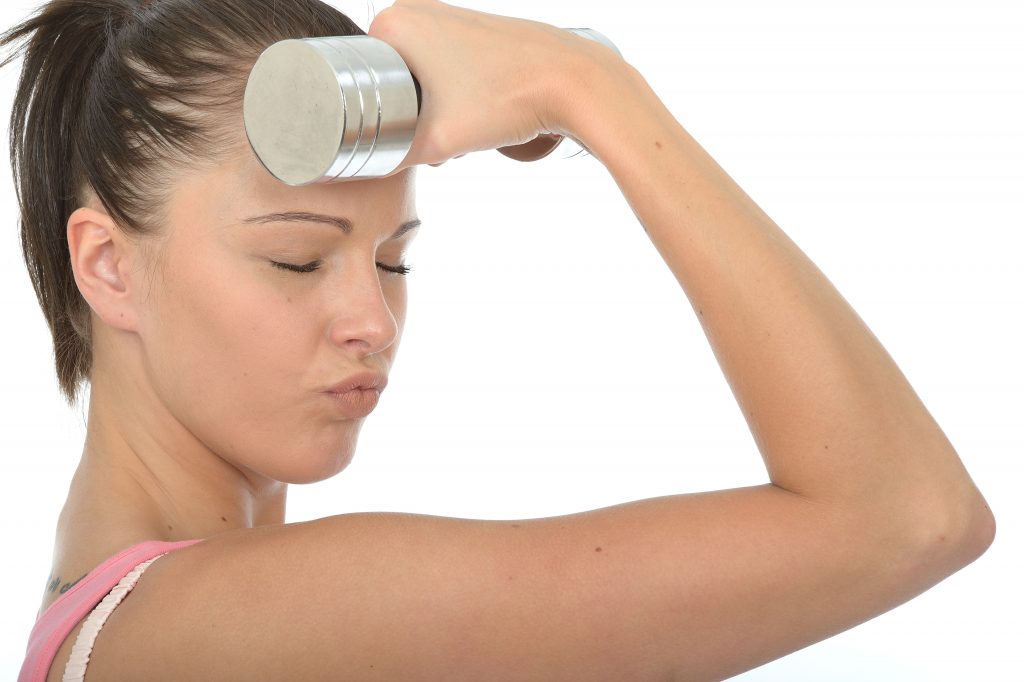Healthy Young Woman Holding a Dumb Bell Weight to Her Forehead With Her Eyes Closed